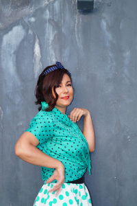 Side view portrait of mature woman standing by gray wall