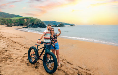 Couple with fat bike taking a selfie with the mobile on the beach
