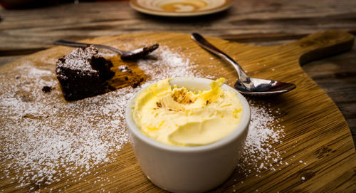 High angle view of clotted cream and brownie with flour on cutting board