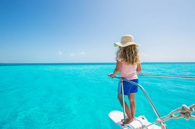 Rear view of woman standing by sea against clear sky