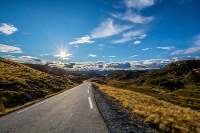 Road leading towards mountains against sky