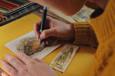 Cropped image of woman drawing on paper