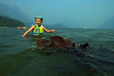 Boy swimming with dog in sea