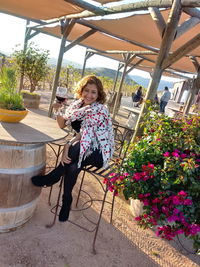 Full length of young woman using mobile phone while sitting outdoors