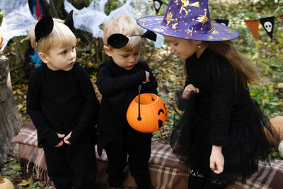 Happy kids in halloween costumes having fun in halloween decorations outdoor