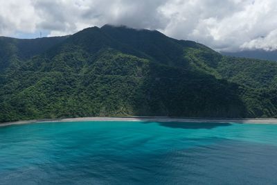 Scenic view of sea by mountains against sky