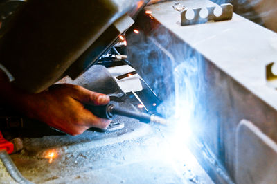 Cropped hand of welder welding metal in factory