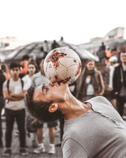 Group of people playing soccer ball in city against sky