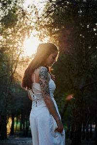 Side view of woman standing against tree