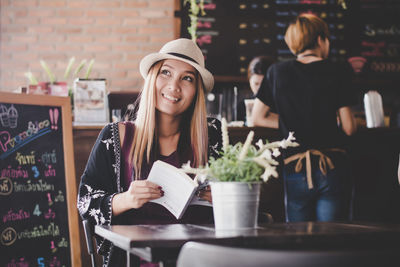 Portrait of young woman standing at restaurant