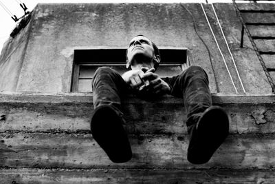 Man sitting in balcony of abandoned building