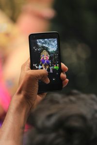 Cropped hand photographing ganesha statue with smart phone