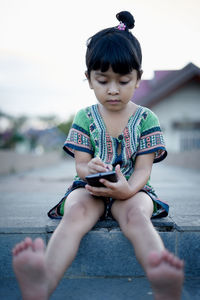 Girl using phone while sitting on land