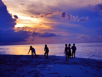 Silhouette people on beach against sky during sunset