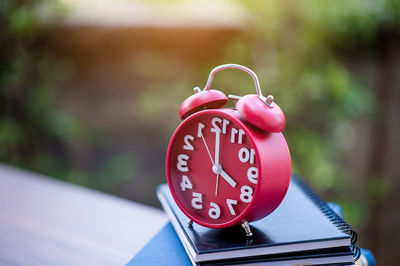 Close-up of alarm clock on books over table