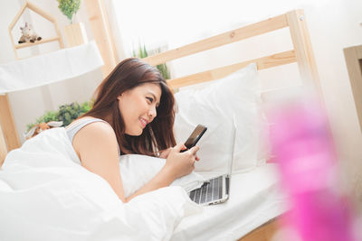 Young woman using mobile phone on bed