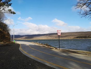 Scenic view of road sign against sky