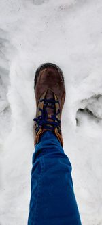 Low section of person standing on snow covered field