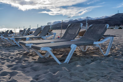 Chairs on beach against sky