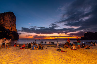 People on beach against sky during sunset