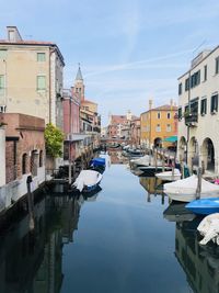 Canal amidst buildings in city against sky