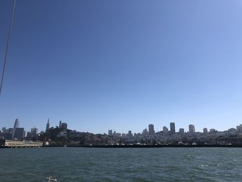 Sea by buildings against clear blue sky