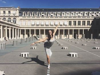 Portrait of young woman standing against building in city