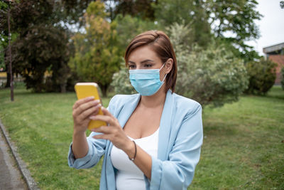 Portrait of young woman using mobile phone in park