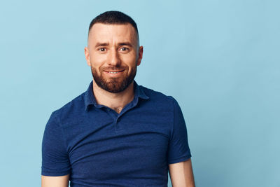 Portrait of young man standing against blue background