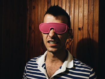 Young man wearing novelty glasses against wooden wall