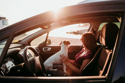 Woman with dog sitting in car