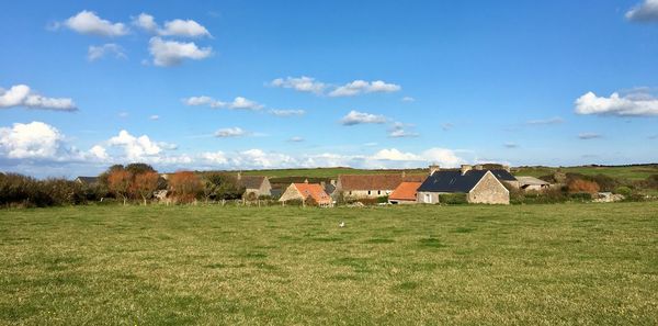 Houses in village on field against sky