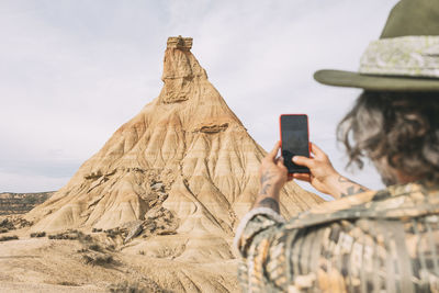 Man taking a photo of castil de tierra, which is a geological formation in spain.
