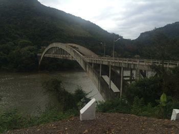 Arch bridge over river against sky