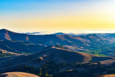 Stunning  heavenly mountain top view of marine layer at sunset with idyllic green meadow valley