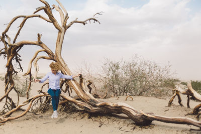 Woman sitting on dead tree