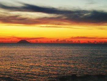 Scenic view of sea against dramatic sky during sunset