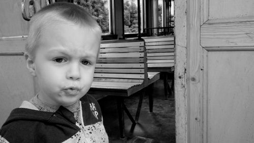 Close-up portrait of cute boy puckering by doorway