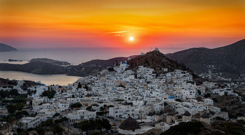 Aerial view of townscape by sea against orange sky