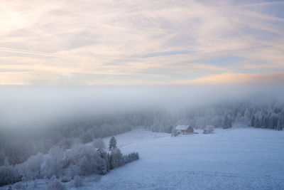 Scenic view of snow covered landscape against cloudy sky during foggy weather