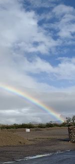Scenic view of rainbow over field against sky