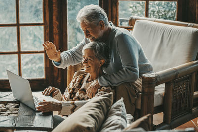 Side view of friends using digital tablet while sitting on railing