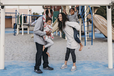 Happy family playing outside at park playground at dusk