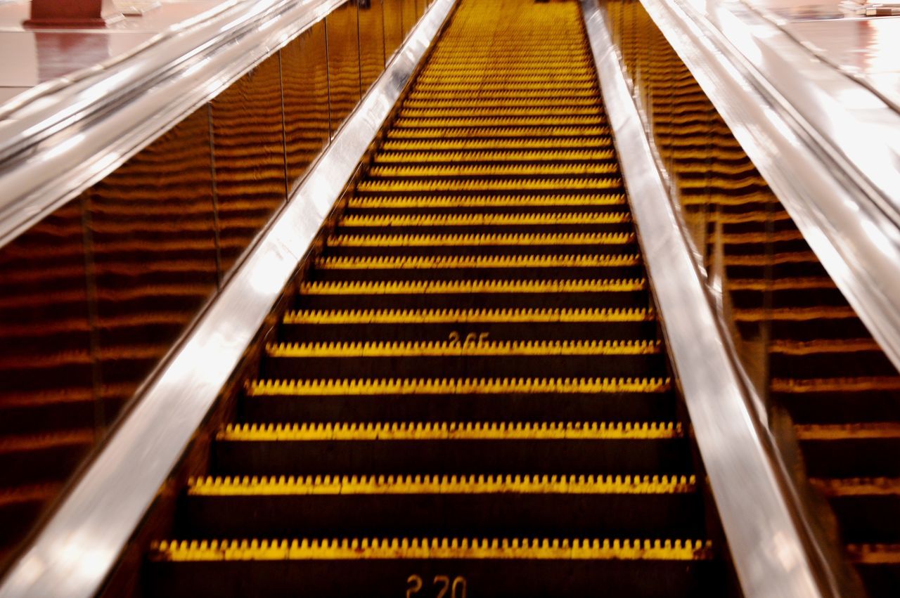 HIGH ANGLE VIEW OF ESCALATOR IN ILLUMINATED STAIRCASE