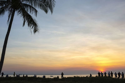 Silhouette people on beach against sky during sunset