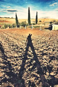 Shadow of person on plough field against sky