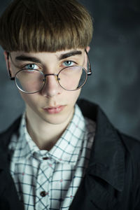 Portrait of young man wearing eyeglasses against wall