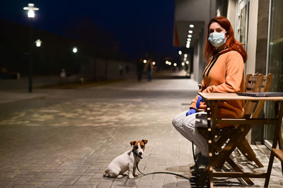Rear view of woman with dog on street at night