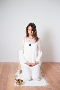 Beautiful woman during a meditation sesion. dressed with white clothes, empty room, wooden floor