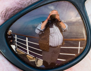 Reflection of young woman photographing on side-view mirror